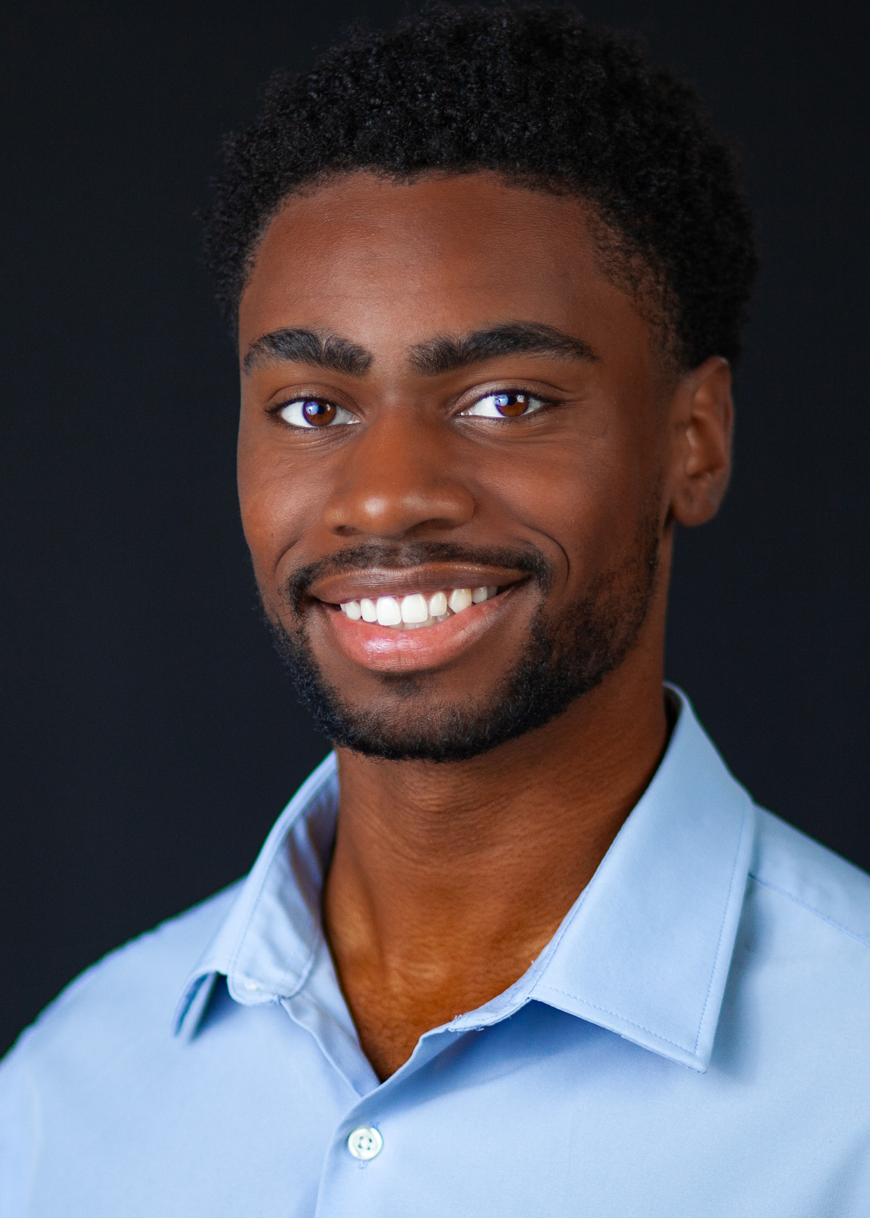 Brandon Dean Milligan warm smiling commercial headshot in a light blue shirt