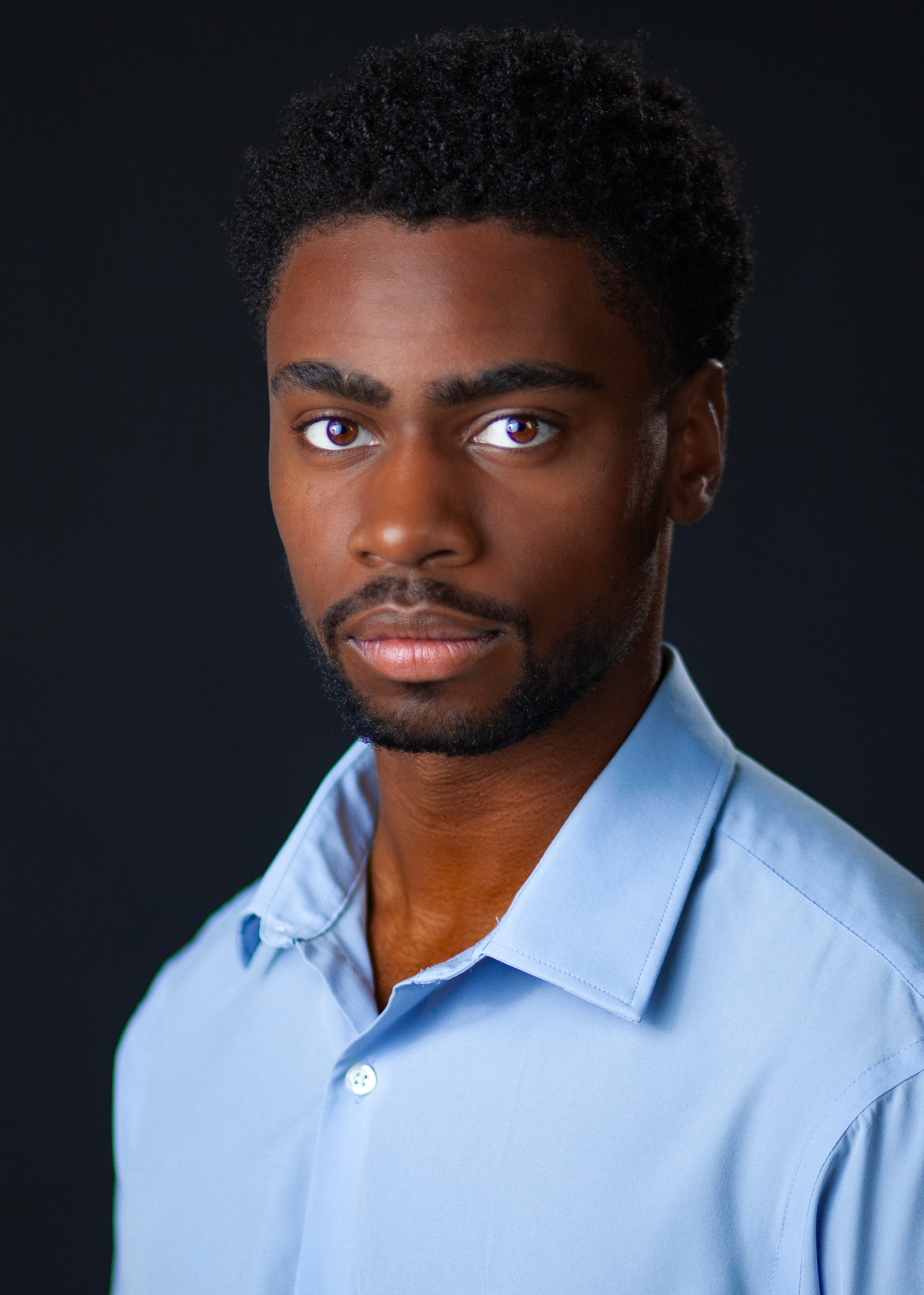Brandon Dean Milligan intense theatrical headshot in a light blue shirt